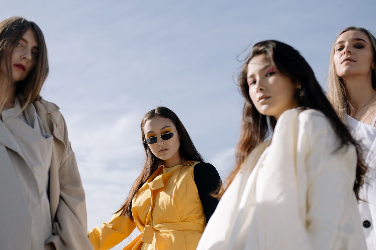 Fashionable women posing confidently in chic outfits under the clear sky.